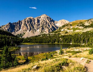 Sunny mountain peak looms over a calm lake with verdant trees