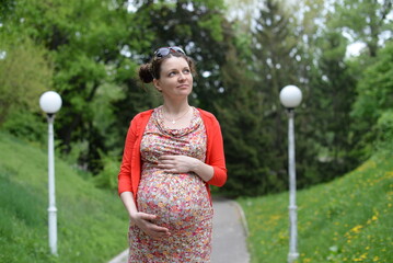 pregnant girl in a dress and red blouse in the park