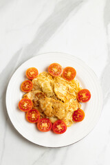 Pasta dish with grilled chicken and cherry tomatoes on white plate