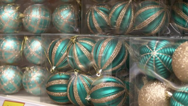 Festive shimmering striped decorations, Closeup view of glittering holiday ornaments display, Restocking shelf with sparkling striped ornaments and glittered baubles in transparent