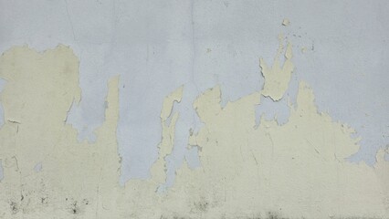 Old concrete wall painted yellow, peeling paint, scratches, dilapidated wall, wall has a cracked yellow surface of rough concrete.