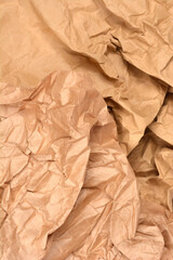 A full-frame close-up of a textured surface composed of crumpled and wrinkled brown kraft paper, perfect for an organic or recycling themed background