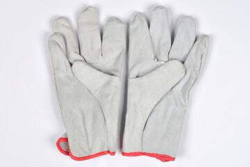 A pair of gray leather work gloves with red trim is shown on a white background