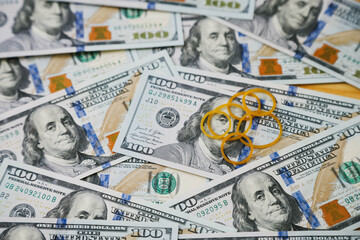 A collection of hundred-dollar bills scattered on a surface with two yellow rubber bands placed in the center.