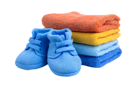 Pair of blue baby booties next to a stack of colorful folded towels on a black background