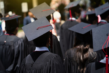 A group of graduates are standing in a field wearing black gowns and caps