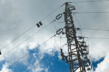 sagoma di un traliccio e cavi dell'alta tensione in primo piano, con cielo nuvoloso, di giorno, sullo sfondo