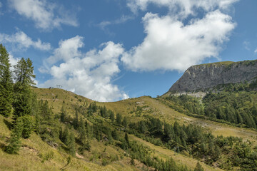 pendii e cime erbose e rocciose, sotto un cielo azzurro e parzialmente nuvoloso, tra le montagne del nord Italia, in autunno