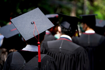 Obraz premium A group of people wearing graduation caps and gowns. The person in the center is wearing a black cap with a red tassel