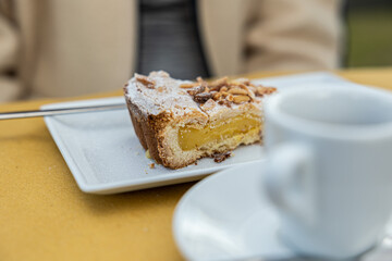 fetta di crostata con crema e pinoli, vicno ad una tazza di caffè