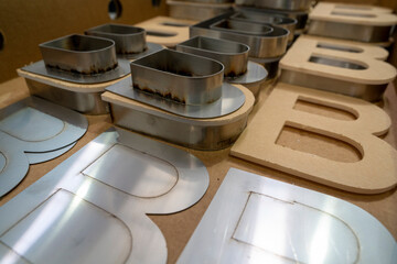 Stainless steel channel letter shells aligned with routed wooden molds
