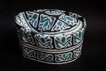 Traditional Omani cap with intricate turquoise and white embroidery, representing rich Gulf heritage and Islamic craftsmanship.