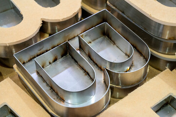 Stainless steel channel letter shells aligned with routed wooden molds