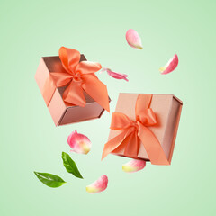 Gift boxes and flower petals flying in air on pastel background