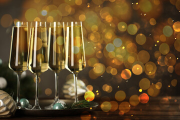 Sparkling wine in glasses and festive decor, bokeh lights. New Year greeting card