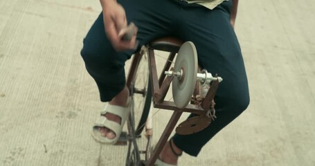 A worker giving the edge to a knife using a grinding wheel - Powered by Adobe