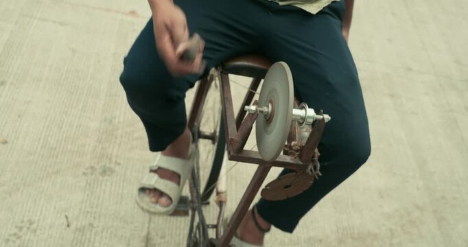 A worker giving the edge to a knife using a grinding wheel