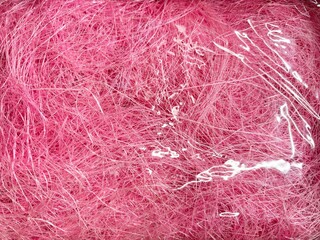 Close-up of bright pink fibrous material wrapped in clear plastic, vivid texture ideal for craft design or decorative background