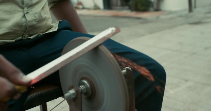 A worker giving the edge to a knife using a grinding wheel