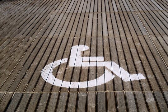 Panneau PMR (Personnes &agrave; Mobilit&eacute; R&eacute;duite) sur un plancher en bois de terrasse ext&eacute;rieure.