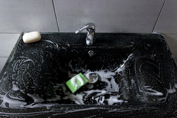 Modern black bathroom sink with chrome faucet, colorful sponges and soap.
Cleaning products quickly and effectively remove dirt and grease from the sink, ensuring perfect cleanliness.