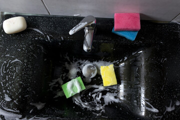 Modern black bathroom sink with chrome faucet, colorful sponges and soap.
Cleaning products quickly and effectively remove dirt and grease from the sink, ensuring perfect cleanliness.