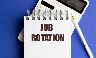 JOB ROTATION phrase on spiral notebook with calculator and pen on blue background documentation