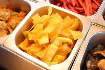 Delicious crispy chips, ready to be served. The image shows freshly made potato chips in metal container