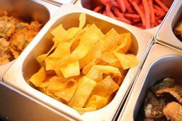 Crispy chips in a metal tray at a buffet display
