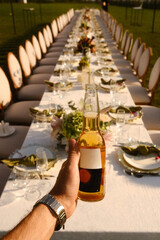 sunset dinner celebration, individual extending drink towards table as sun sets with festive