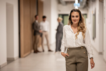 Fototapeta premium Confident businesswoman walking office corridor smiling