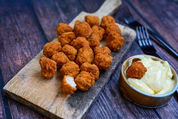 Crispy  deep fried   chicken  popcorn  nuggets and french fries . Breaded  with Cornflakes chicken  Breast fillets  with chilly peppers and fresh   basil on wooden rustic background
