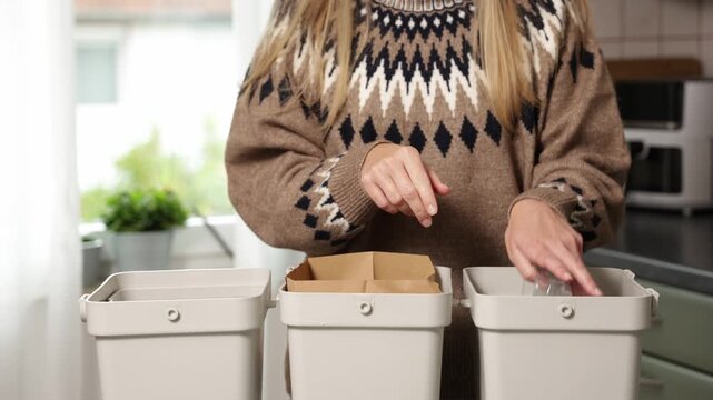 Woman sorting waste at home, placing items into bins, camera follows action closely
