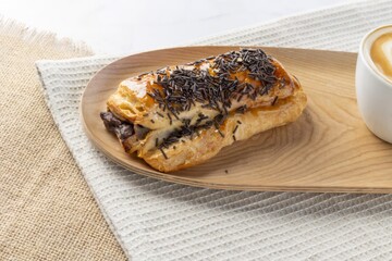 Puff pastry chocolate roll with sprinkles and cappuccino