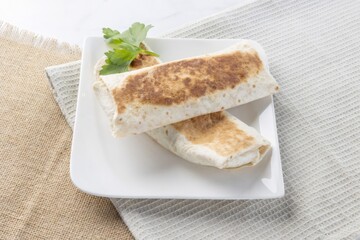 Two burritos on plate with parsley ready for eating