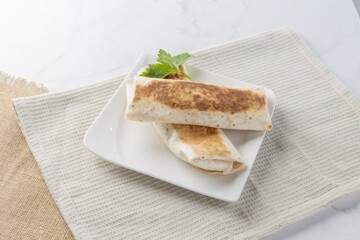 Grilled burritos on white plate with parsley garnish