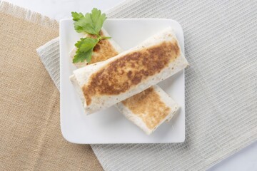 Two savory grilled burritos on white plate