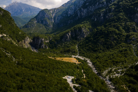 Aerial view of a hidden valley with lush green forests contrasting with the rugged, rocky terrain of the Dinaric Alps, Theth, Shkoder County, Albania.
