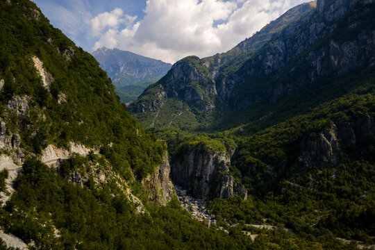 Aerial view of jagged peaks and lush forests converge in a symphony of green and grey, under the vast Albanian sky, Theth, Shkoder County, Albania.