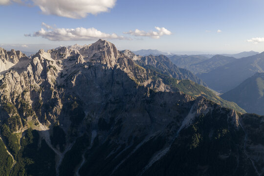 Aerial view of jagged mountain peaks rise majestically against the sky, casting long shadows across the verdant valleys, Teth, Shkoder County, Albania.