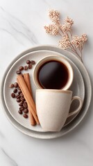 Top View of a Rustic Ceramic Mug Filled with Dark Coffee Beside Coffee Beans and Cinnamon Sticks on a Speckled Plate with Dried Flowers on a Marble Background