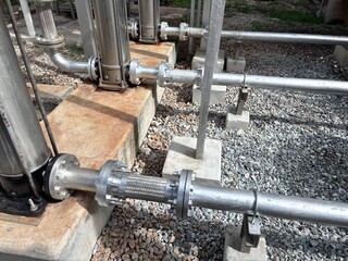 Industrial stainless steel piping system with flexible metal hose connectors and flanges on...