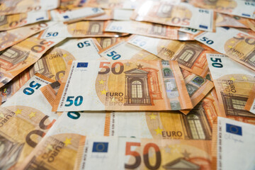 Close up of 50 Euro banknote with shallow depth of field on stacked pile of cash representing business focus and wealth