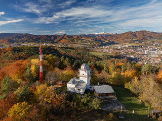 Aerial view of Vartovka astronomical observatory and a red and white tower amidst a vibrant tapestry of autumn foliage, Banska Bystrica, Banskobystricka kraj, Slovakia.