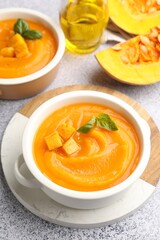 Delicious pumpkin cream soup with basil served on grey table, closeup
