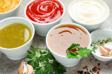 Different sauces, spices and herbs on light table, closeup