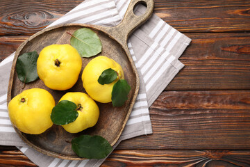 Fresh ripe quinces with leaves on wooden table, top view. Space for text