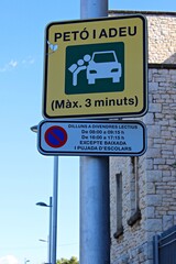 Fototapeta premium Funny Catalonia traffic sign 'Petó i Adeu' (Kiss and Go) indicating a short stop zone near a school, photographed on a sunny day in Spain.