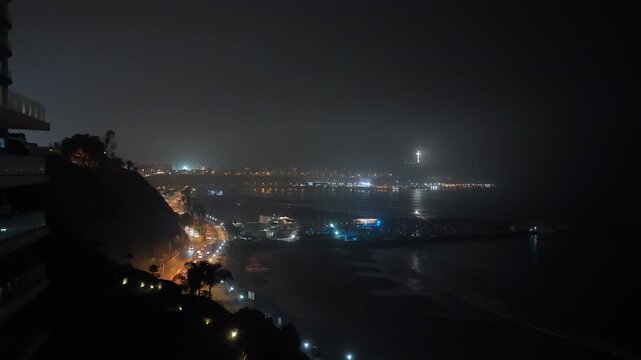 Aerial view captures misty nighttime glow of Lima, Peru's twinkling city lights along the coast, revealing modern apartment building