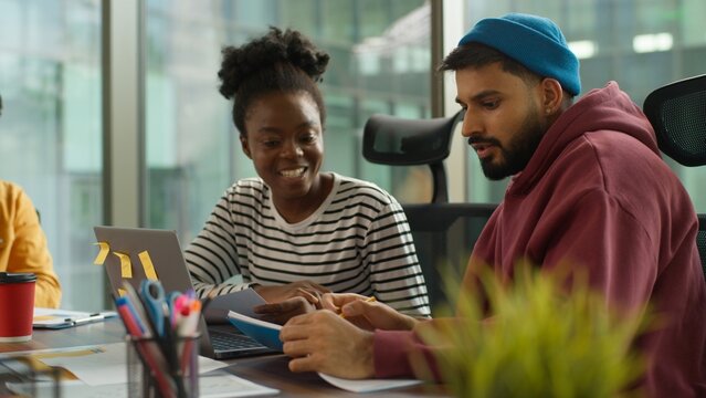 Multi-Ethnic entrepreneurs of informal business startup in office meeting diverse team work process in company workgroup, African American woman talk with Indian Arabian man strategy session planning